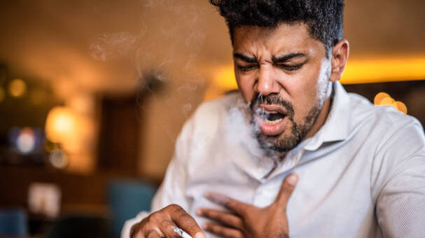 an smoking a cigarette in bar and coughing.